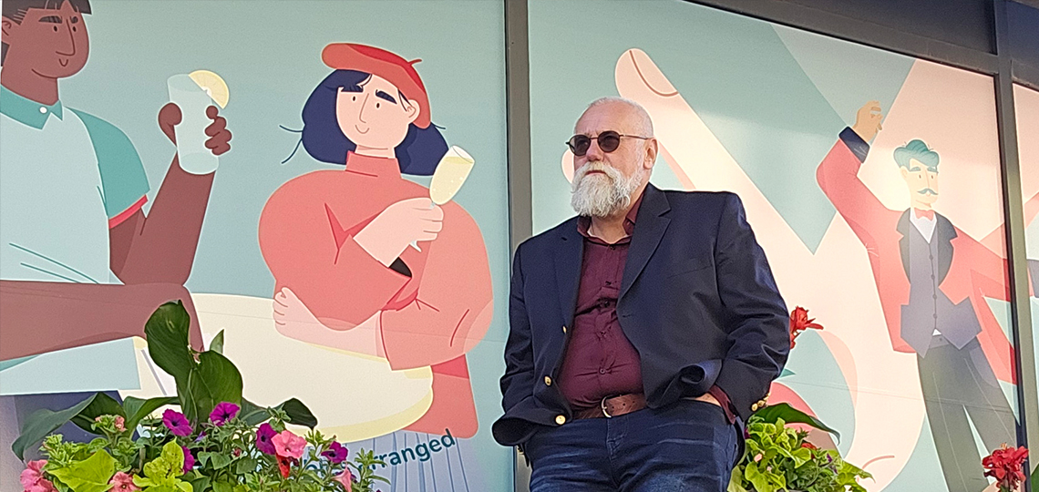 Stephen Dafoe standing against a colorful illustrated backdrop, wearing a blazer and sunglasses, blending storytelling, media expertise, and urban culture.