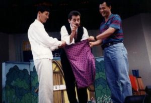 Stephen Dafoe performing a magic act on stage in South Korea in 1995, engaging the audience with a comedic illusion involving two volunteers.